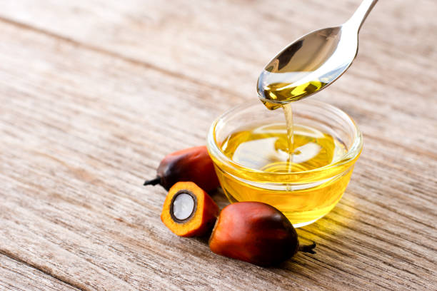 Palm oil in glass bowl and fresh palm fruit on wooden table background.